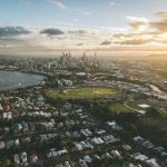 Vista aérea de Brisbane ao entardecer, com o rio sinuoso, a paisagem urbana e o horizonte da cidade.