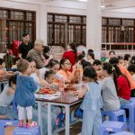 Crianças e adultos participam de uma atividade artesanal em um espaço comunitário.