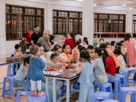 Crianças e adultos participam de uma atividade artesanal em um espaço comunitário.