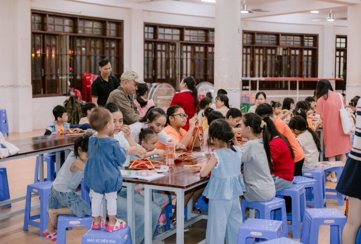 Crianças e adultos participam de uma atividade artesanal em um espaço comunitário.