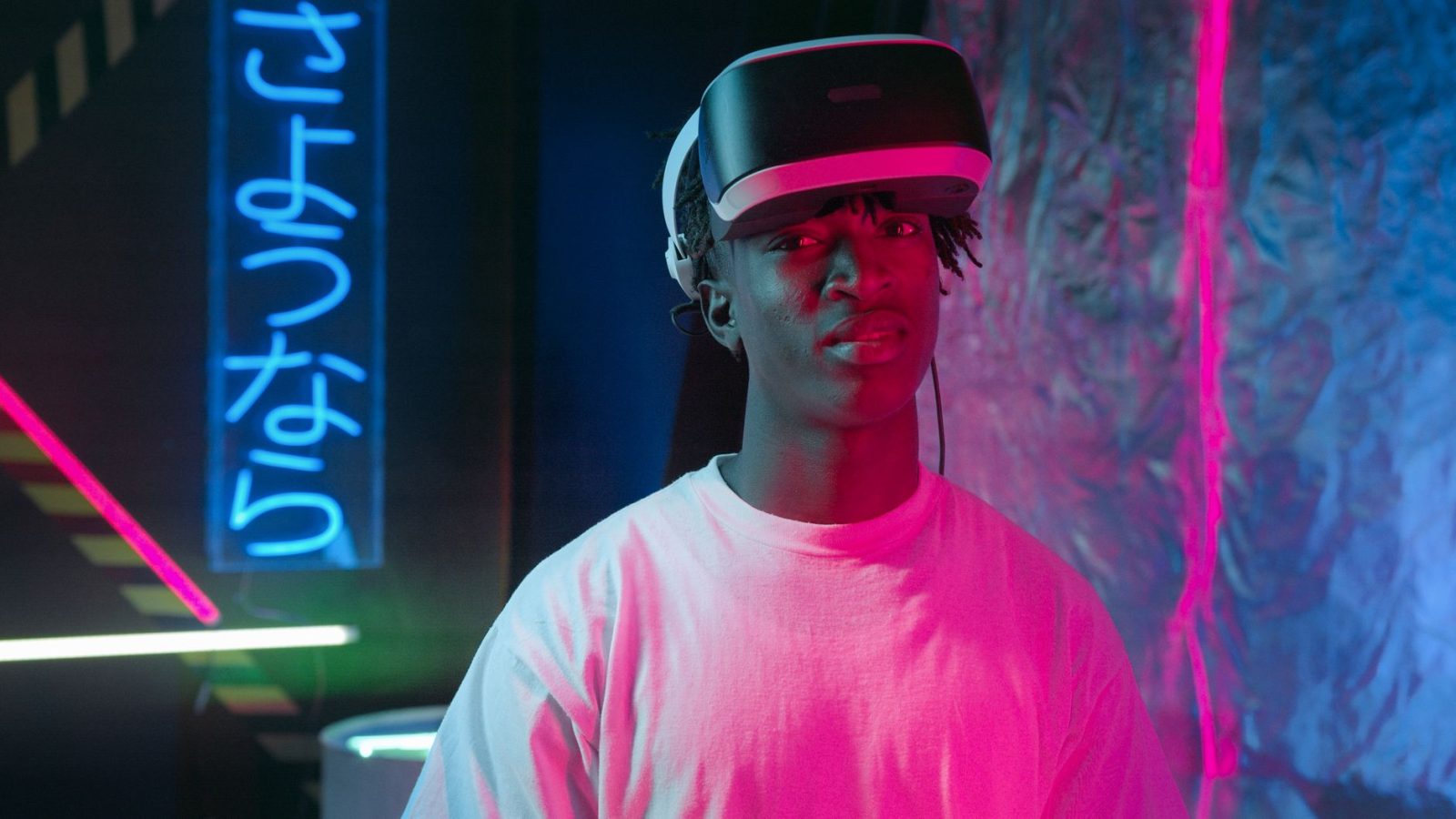 Pessoa usando óculos de realidade virtual iluminada por luzes neon em um ambiente escuro.