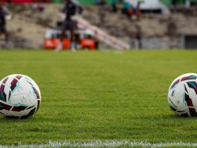 Duas bolas de futebol sobre o gramado de um estádio antes de uma partida.
