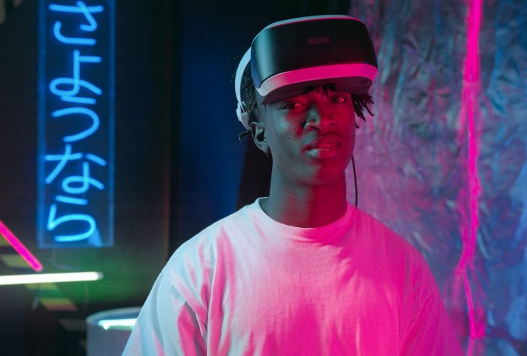 Pessoa usando óculos de realidade virtual iluminada por luzes neon em um ambiente escuro.